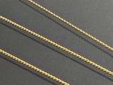 three gold chain necklaces on a black surface