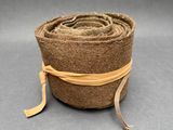 rouleau de laine marron enroulé, orné d'un ruban jaune, sur fond gris