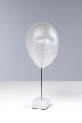 une photo d'une sculpture représentant un visage, posée sur un socle en marbre