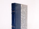 an old book with a blue cover sitting on top of a white surface
