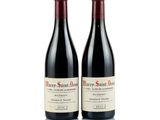 two bottles of red wine sitting next to each other on a white surface