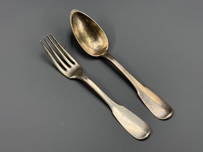 deux cuillères et une fourchette posées sur une table, sur fond noir