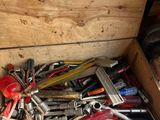 une caisse en bois remplie de divers outils, posée par terre