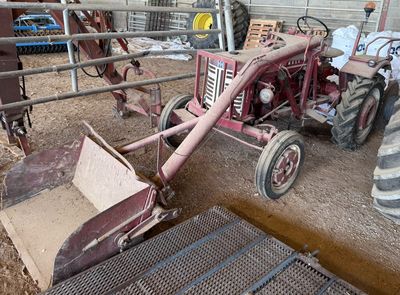 un tracteur qui est à l'abandon dans la boue, dans une grange