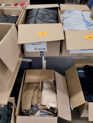 Des cartons de vêtements sont empilés les uns sur les autres dans un entrepôt.