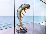 a statue of a fish on a pedestal in front of a window