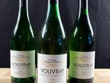 trois bouteilles de vin posées sur une table en bois