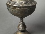 an ornate silver bowl with a lid on a pedestal