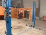 deux ponts élévateurs bleus dans un garage, avec un camion rouge en arrière-plan