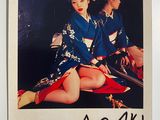 an old photo of a woman in a kimono sitting on a red blanket