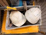 deux casques de chantier posés dans une boîte sur un chariot