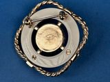 a close up of a gold and silver broochle on a blue background