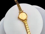 a gold watch sitting on top of a white plate