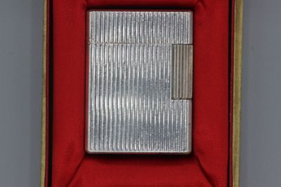un vieux briquet en argent dans une boîte rouge posée sur une table