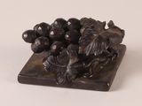 a statue of a bunch of grapes on top of a wooden block