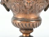 a bronze vase with a face on it on a table