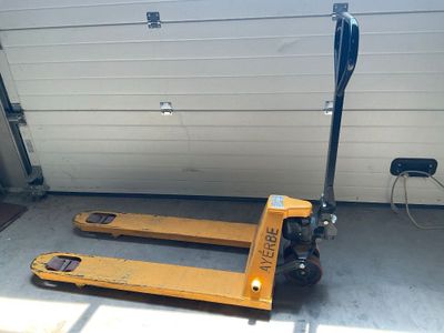 un chariot élévateur jaune garé devant la porte d'un garage