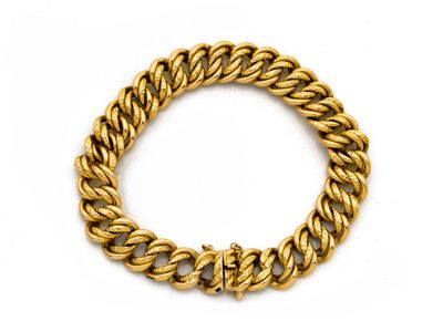 gros plan d'un bracelet en chaîne en or sur fond blanc