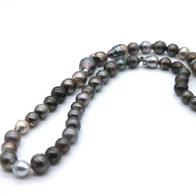 a close up of a strand of black pearls on a white surface