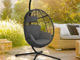 une chaise suspendue noire sur une terrasse en bois dans un jardin