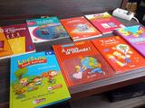 plusieurs livres pour enfants posés sur une table, à côté d'une télécommande