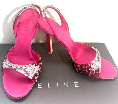 Les chaussures sont roses et argentées, ornées de cristaux rouges.