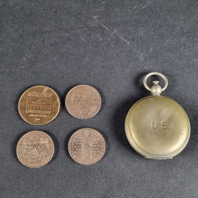 several coins and a pocket watch on a black surface