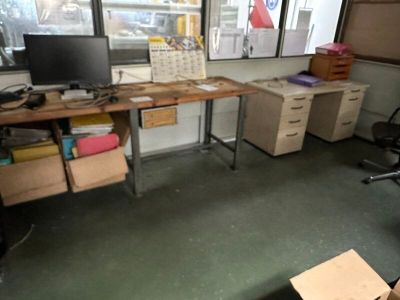 un bureau sur lequel se trouve un ordinateur, dans une pièce où il y a beaucoup de cartons
