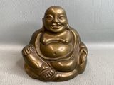 statue d'un Bouddha souriant assis sur une surface blanche