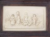 carvings of people and animals are displayed in a frame on a wall