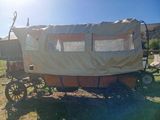 a covered wagon sitting on the grass in a field