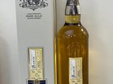 La bouteille de whisky se trouve à côté de la boîte, sur la table.