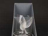 a close up of a glass in a box with a bird on it