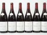 six bouteilles de vin sont alignées sur une surface blanche