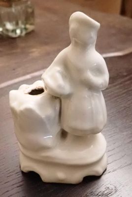 une petite figurine représentant une femme et un chien, posée sur une table