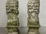 pair of stone lion heads on pedestals in front of a white wall