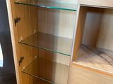 a small cabinet with glass shelves in the corner of the room