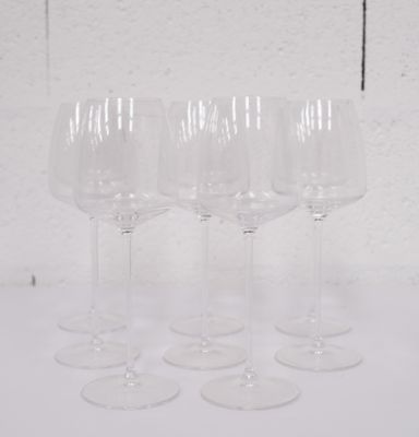 quatre verres à vin vides sont alignés sur une surface blanche