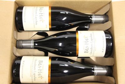 three bottles of wine are in a cardboard box on a table