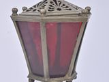 a red glass lamp on a metal pole against a white background