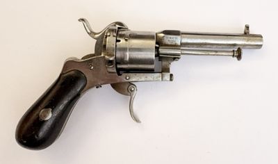 un vieux revolver avec une poignée en bois sur une surface blanche