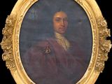 un portrait ovale représentant un homme vêtu d'un manteau rouge, dans un cadre doré