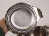 a person holding a silver cup in their hand