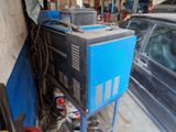 a blue machine sitting in a garage next to a car