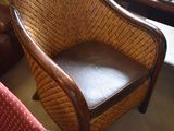 a wicker chair with a leather seat in a room