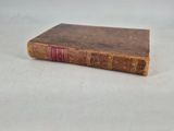 an old book sitting on top of a table on a white surface