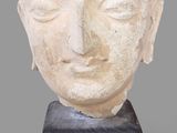 une photo représentant une statue représentant une tête posée sur un socle en bois
