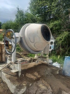 a cement mixer that is sitting on a pile of dirt