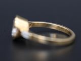 a close up of a gold ring with a diamond on a black surface