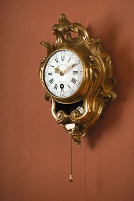 une horloge en or accrochée au mur, avec un pendule